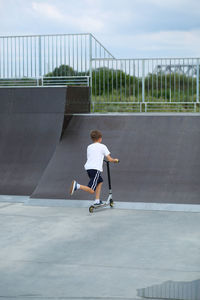 Active ten year old boy riding a scooter in the summer skate park