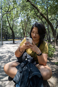 Portrait of a serene asian woman happy using a mobile phone at the park in mexico city