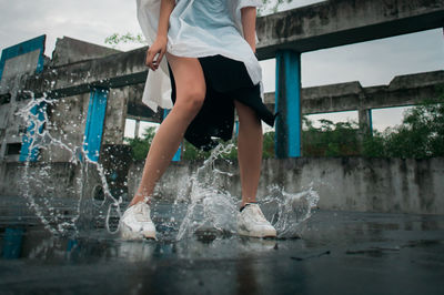 Low section of woman splashing water on road