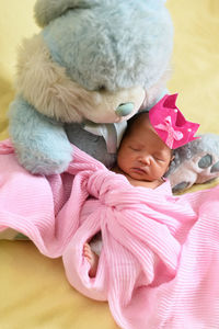 Baby girl with teddy bear and blanket on sofa