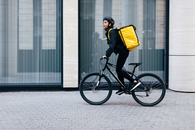 Side view of man riding bicycle on street