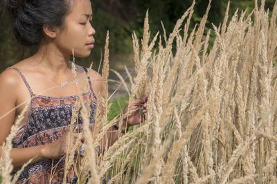 Young woman looking away while standing on field