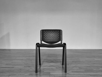 Empty chair on hardwood floor against wall at home