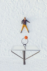 High angle view of man playing basketball in snowy court