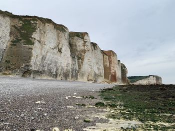 Rock formations on beach against sky