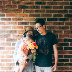 Young couple standing against brick wall