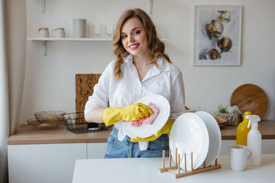 Portrait of smiling young woman using mobile phone while sitting at home