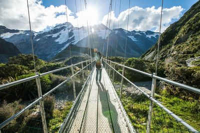 Rear view of woman on footbridge against mountains