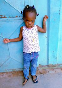 Portrait of cute girl standing against wall