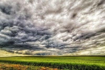 Scenic view of agricultural field against dramatic sky