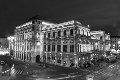 Vehicles on road against buildings at night