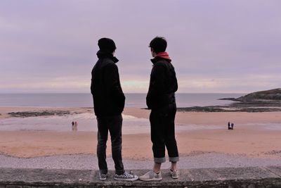 People on beach against sky during sunset