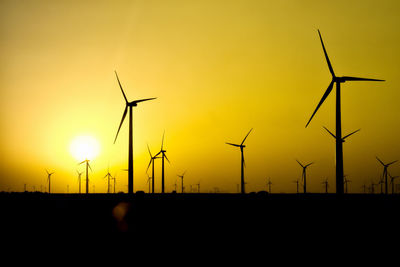 Silhouette wind turbine against sky during sunset