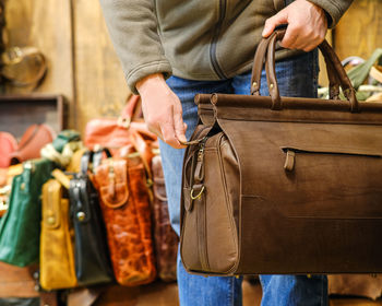 Midsection of man holding leather outdoors