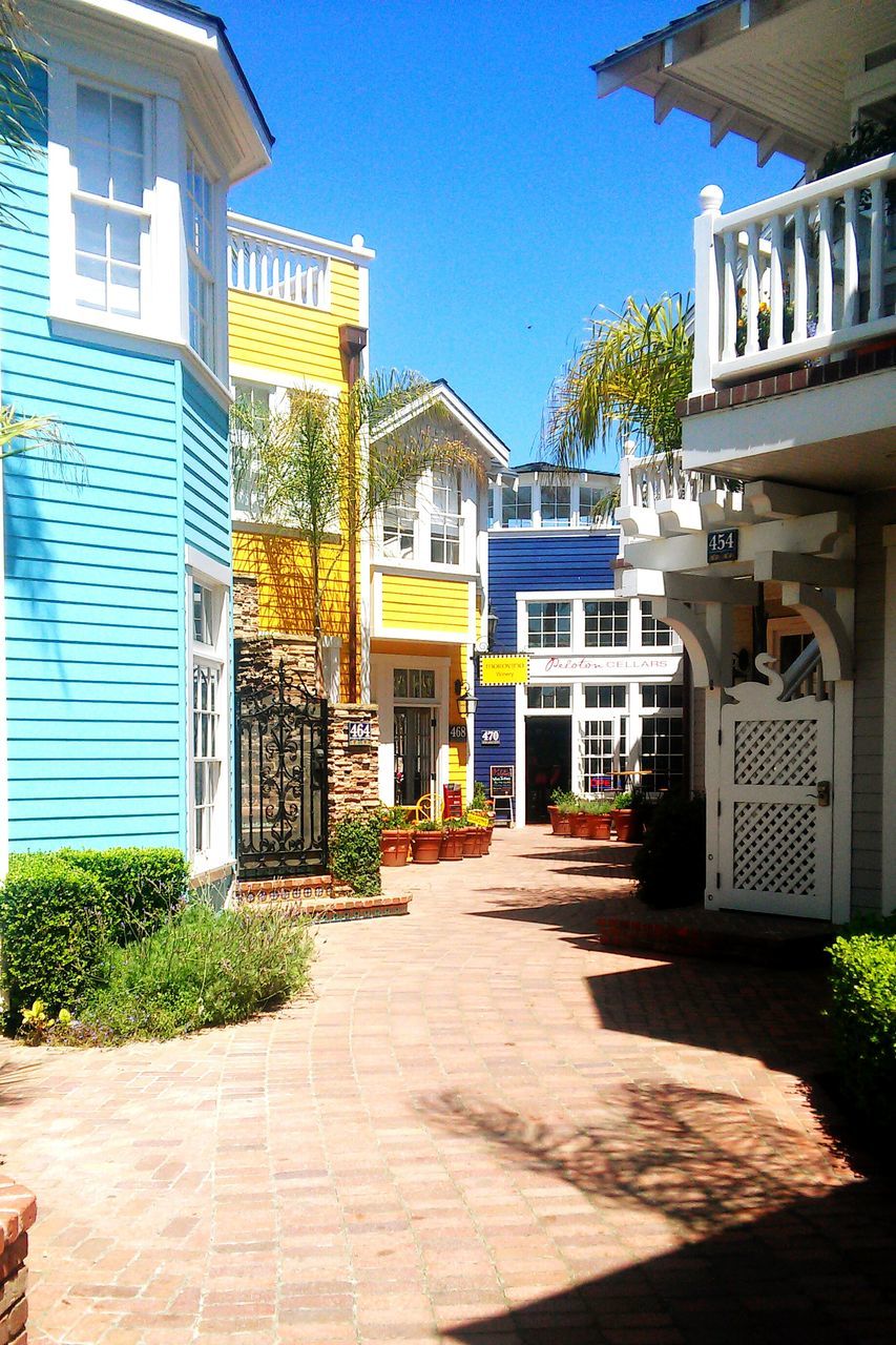 building exterior, architecture, built structure, street, the way forward, city, residential structure, building, residential building, cobblestone, house, sidewalk, sunlight, tree, outdoors, footpath, day, road, empty, blue