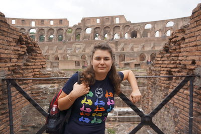 Portrait of young woman against historic building