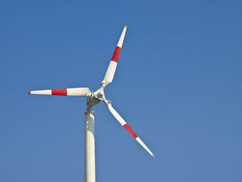 Three blade wind turbine in blue clear sky in sunlight