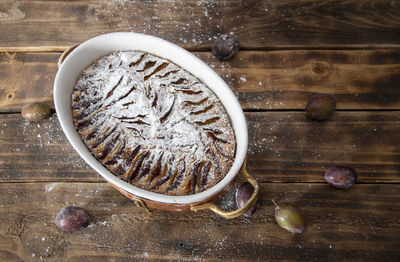 Woman sprinkled with powdered sugar plum cake, baking homemade sweet dessert