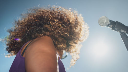 Low angle view of woman singing song against sky