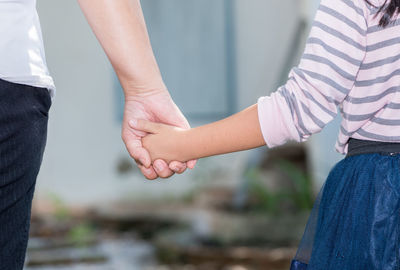 Midsection of mother holding daughter hand