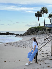 Full length of woman standing at beach against sky