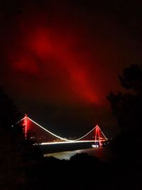 Illuminated suspension bridge against sky at night