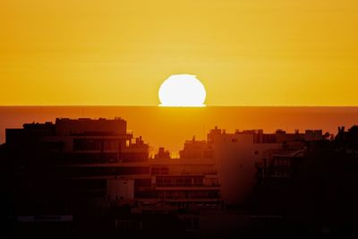 Silhouette buildings against sky during sunset