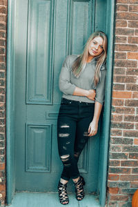 Portrait of young woman leaning against door