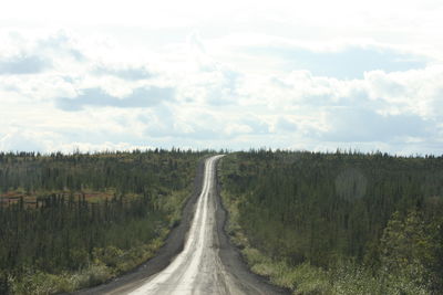 Empty road along trees and landscape against sky