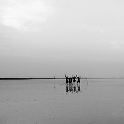 Men standing on beach against sky