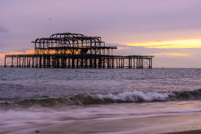 Silhouette structure in sea against sky during sunset