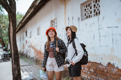 Portrait of young woman standing against wall