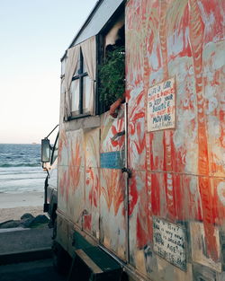 Graffiti on building by sea against sky