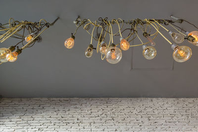 Low angle view of illuminated chandelier hanging on wall at home