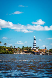 Sea by buildings against blue sky