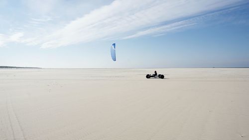 Man kite buggy at beach against sky