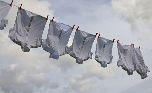 Low angle view of clothes drying against cloudy sky