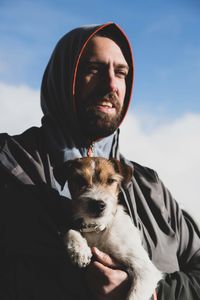 Portrait of man with dog against sky