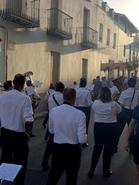 Rear view of people walking by buildings in city