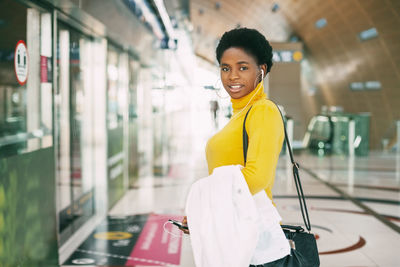 An attractive african woman at a metro station, the girl smiles and looks up thoughtfully.