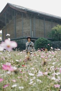 Woman with flowering plants in front of building