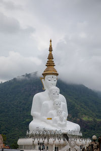 Buddha statue by building against sky