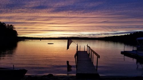 Pier on lake against sky during sunset