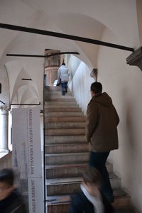 Rear view of people walking on staircase in building