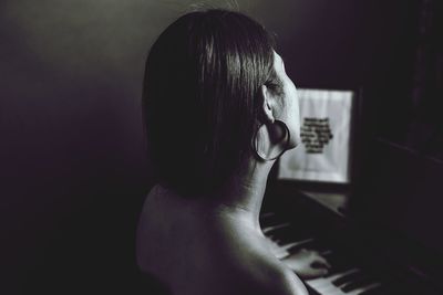 Rear view of woman playing piano at home