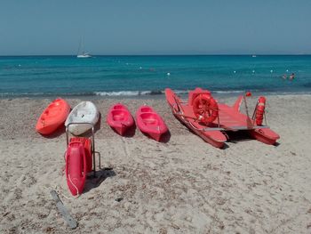 Red deck chairs on beach against sky