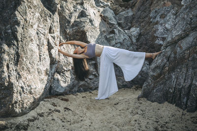 Flexible young ethnic female performing backbend while balancing on one leg during yoga practice between mounts