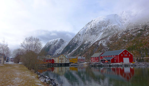 Houses by snowcapped mountains against sky during winter