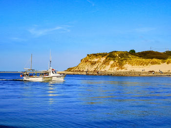 Sailboat sailing on sea against blue sky