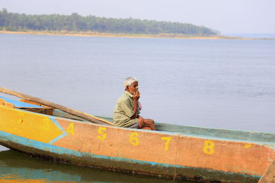 Side view of senior man sitting in boat at sea
